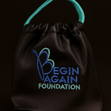 Black drawstring bag with 'Begin Again Foundation' text and logo on a black background