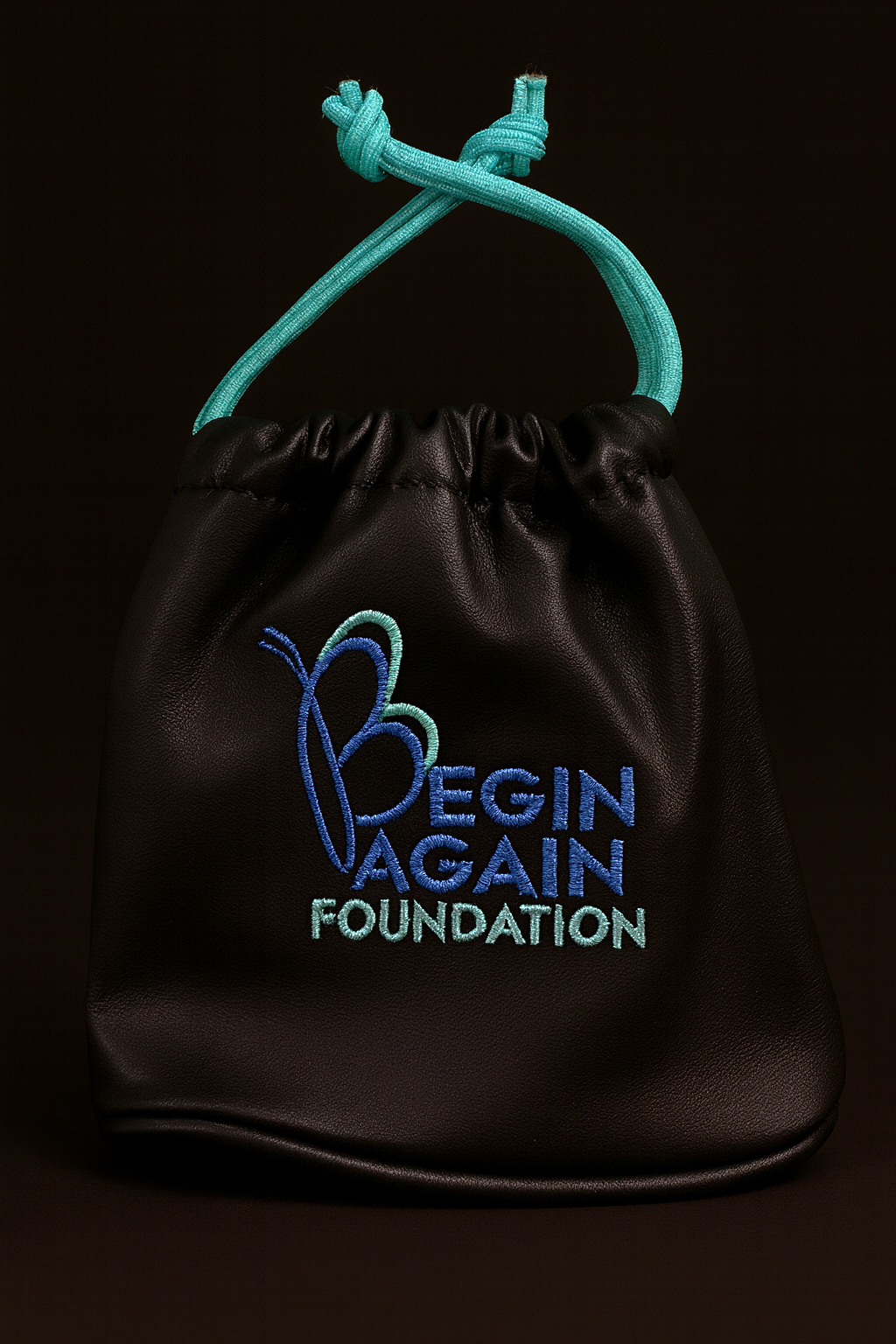 Black drawstring bag with 'Begin Again Foundation' text and logo on a black background