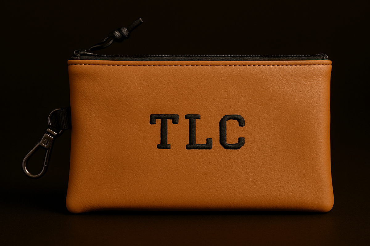Brown leather pouch with 'TLC' monogram on a black background
